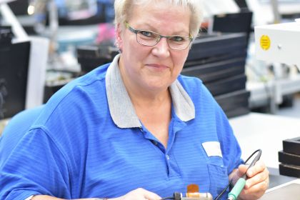 Portrait ältere Frau in einer Fabrik zur Montage von moderner Elektronik am Arbeitsplatz